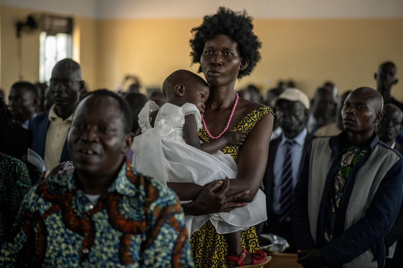 A woman holding her child in a growing congregation