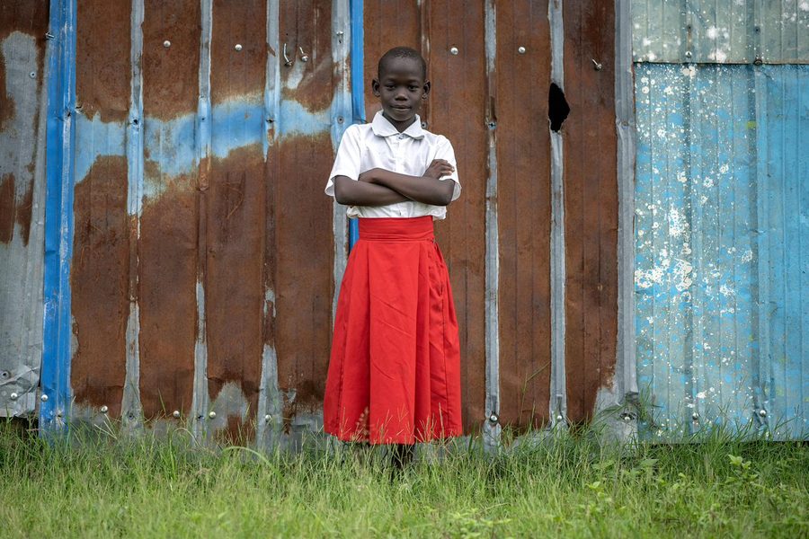 A woman in red and white near a church in Kajo Keji