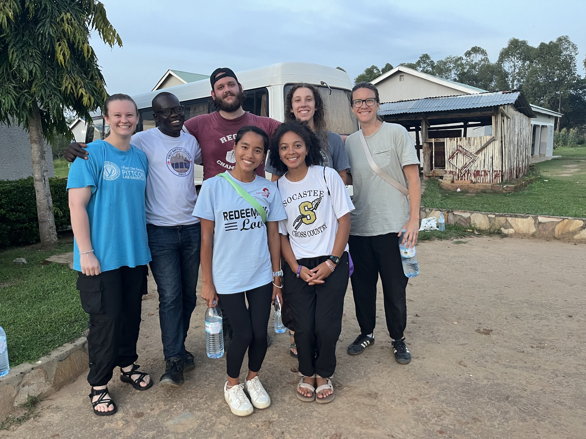 College team and a South Sudanese leader arm in arm after a day of outreach