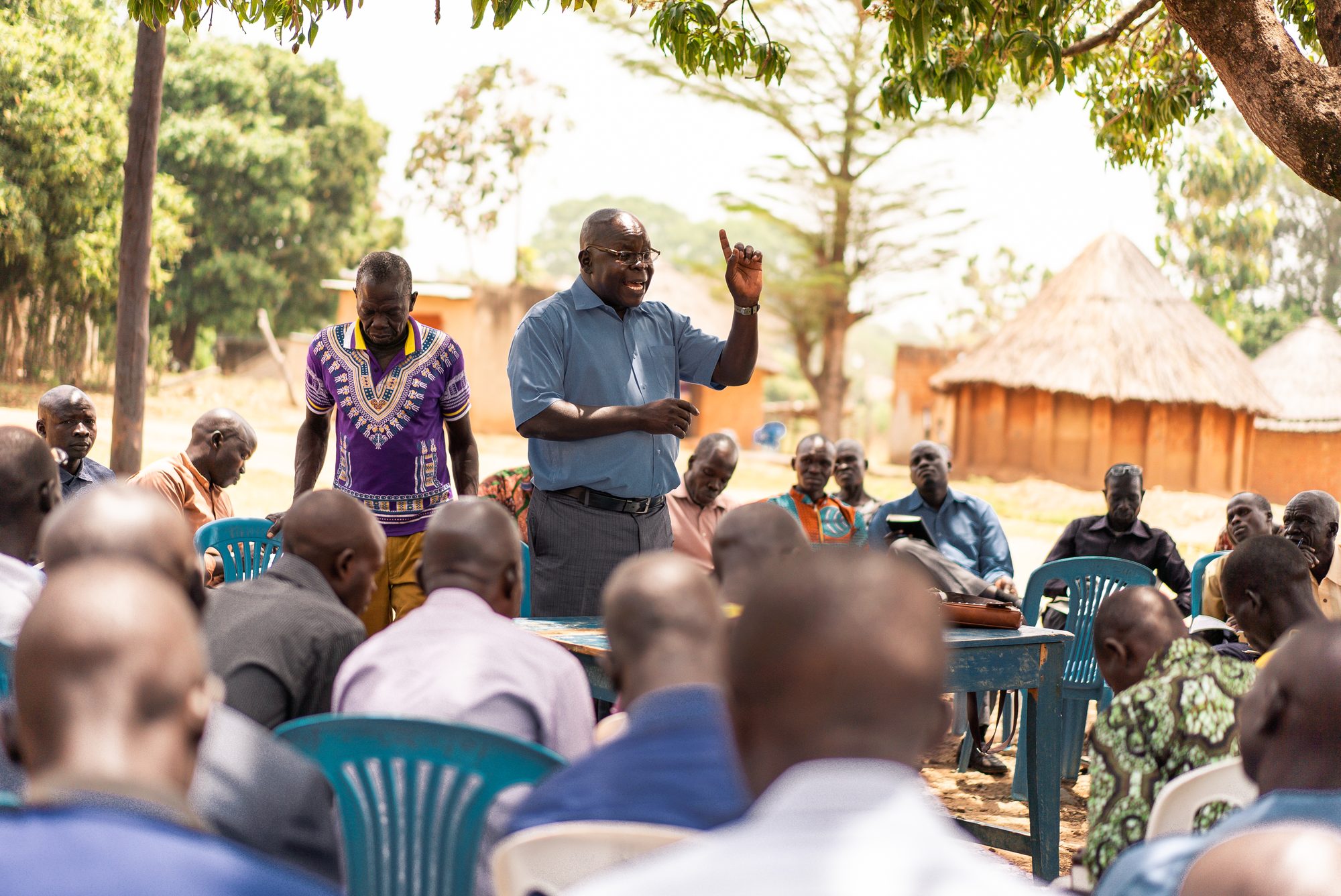 A South Sudanese pastor teaching a gathering of church leaders under a mango tree