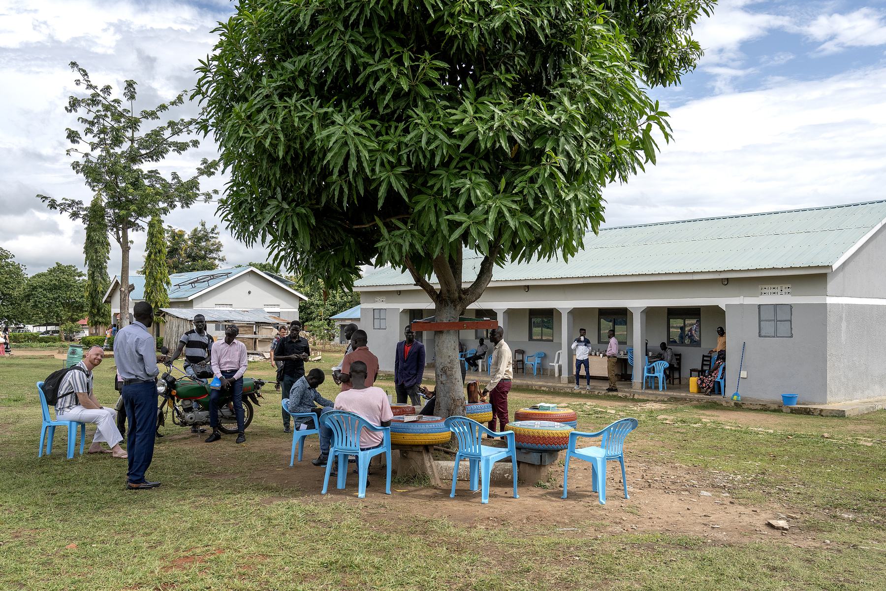 Students and visiting teachers talking together under the tree between classes at NEATS