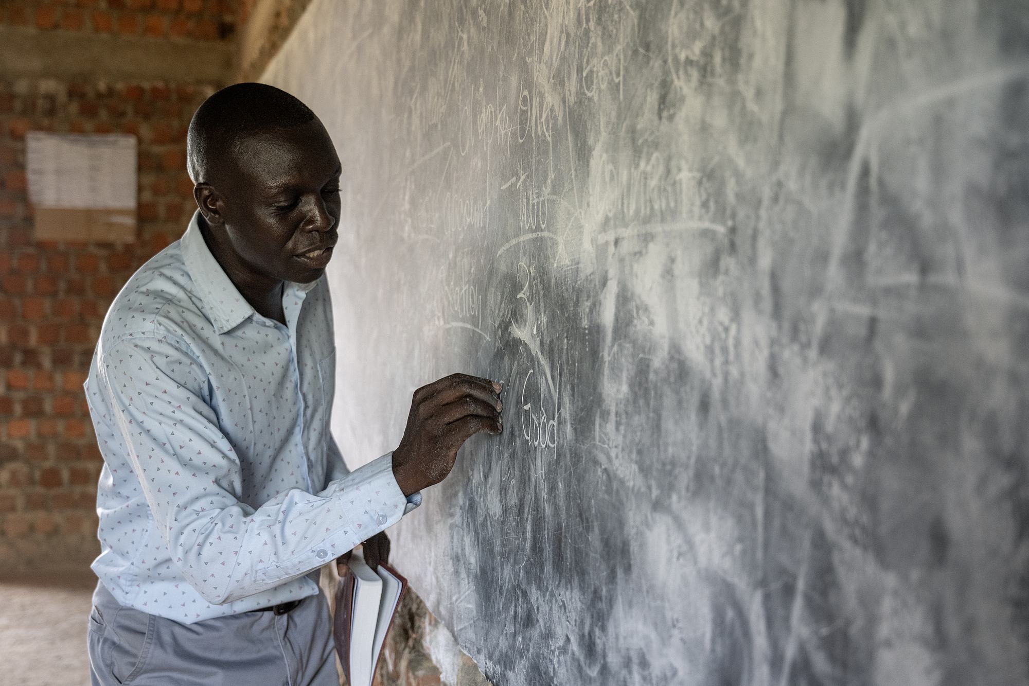 A NEATS teacher writing on the blackboard during a lecture in Kajo Keji, South Sudan
