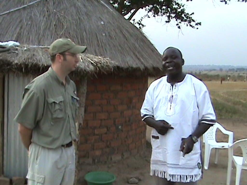 David Kaya teaching beside a brick-and-thatch tukel as Mike Congrove listens, 2008