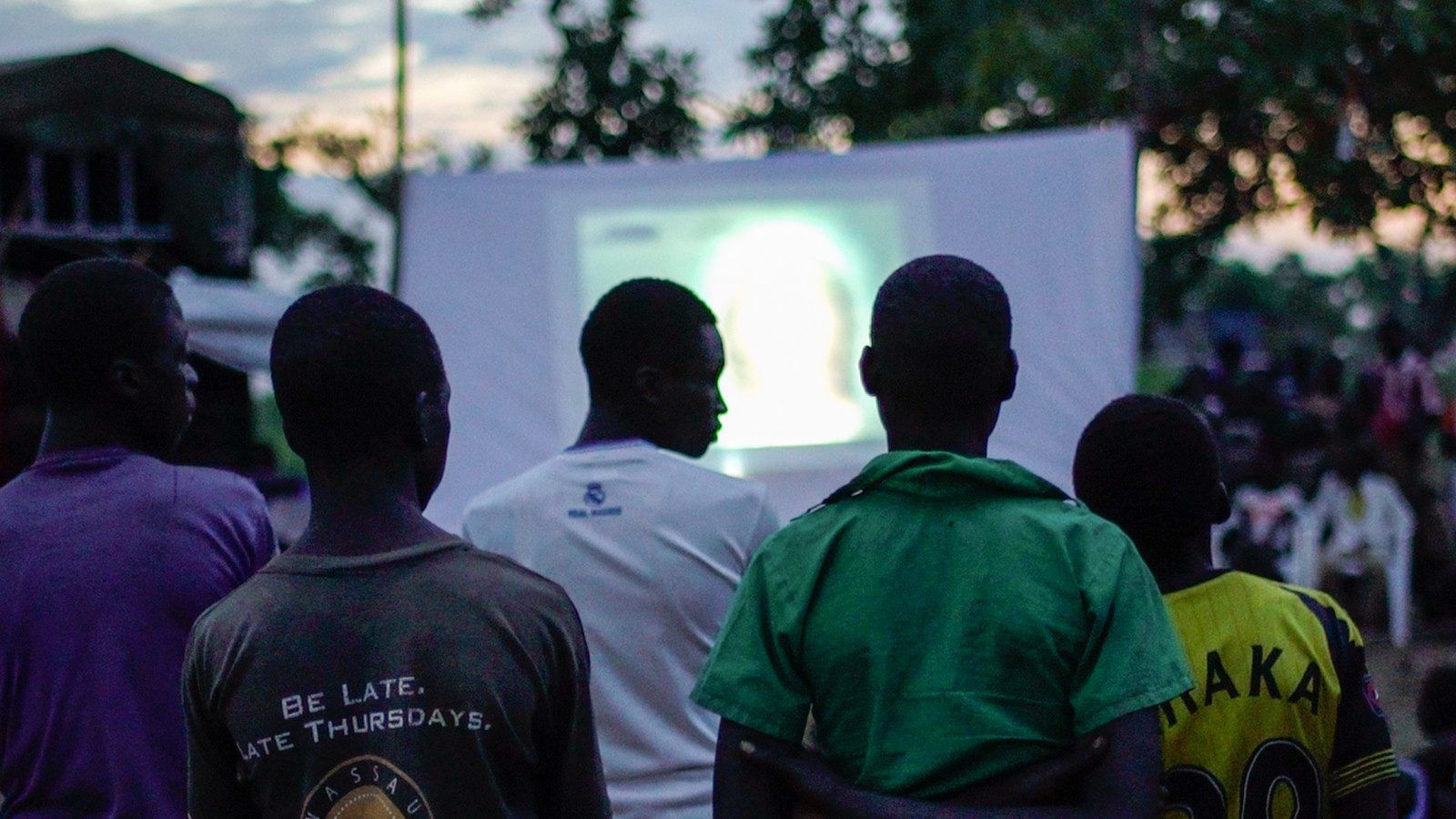 A crowd watching the Jesus Film on an outdoor screen at dusk